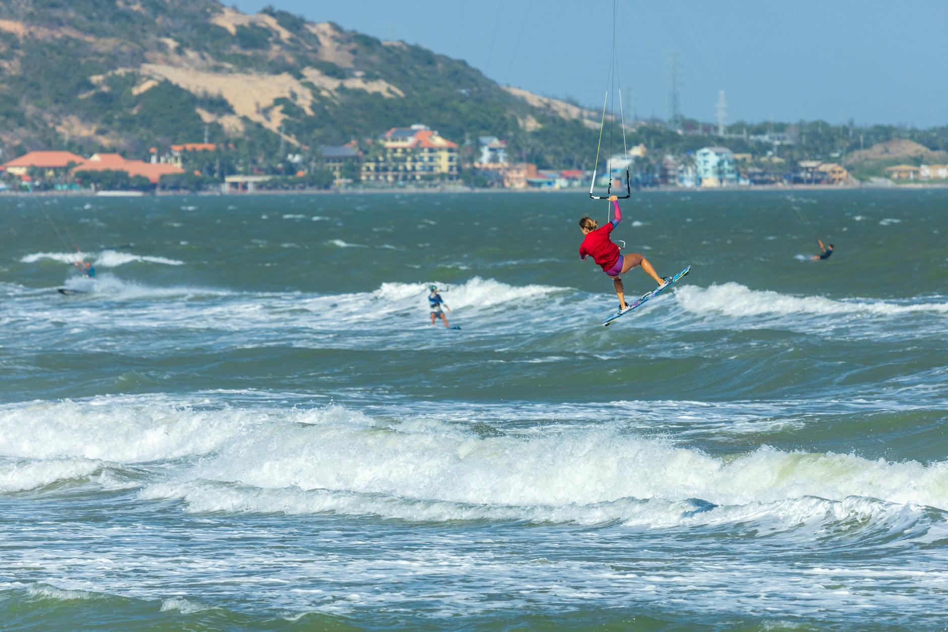 A woman kitesurfing midair, capturing an exhilarating moment in water sports adventure.